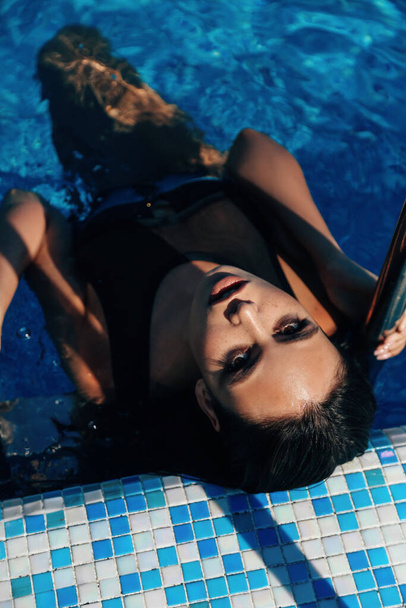 fashion outdoor photo of beautiful sensual woman with dark hair in elegans swimming suit relaxing near swimming pool - Fotó, kép
