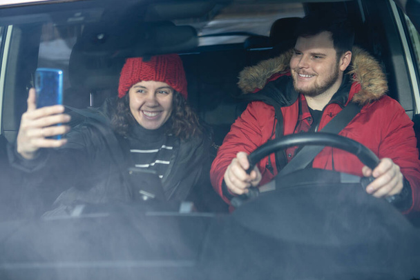pareja en coche en traje de invierno conducir y hablar alquilar un coche - Foto, Imagen