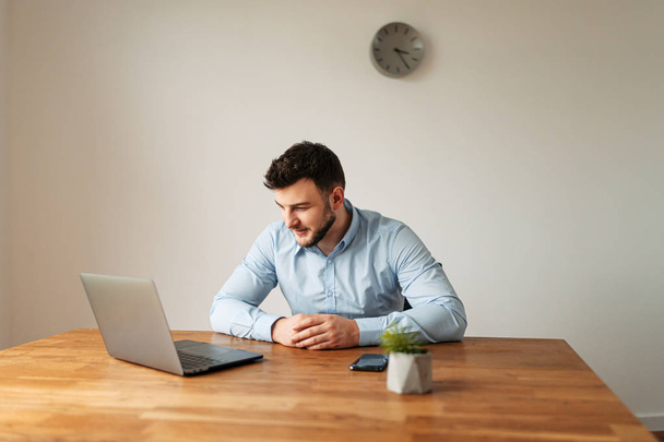 Attractive male office worker is using a laptop - Φωτογραφία, εικόνα