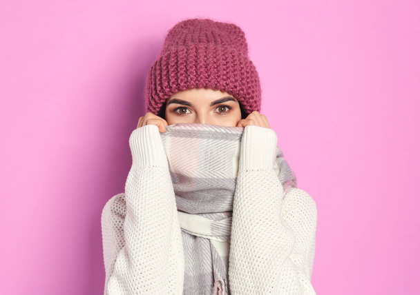 Young woman wearing warm sweater, scarf and hat on pink background. Winter season - Foto, Imagem