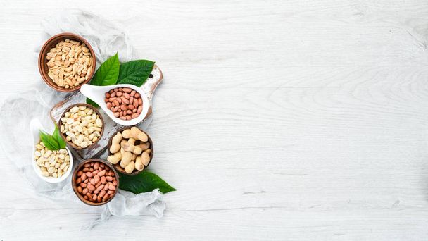 Peanuts in bowls on white wooden background. Nut background. Top view. - 写真・画像
