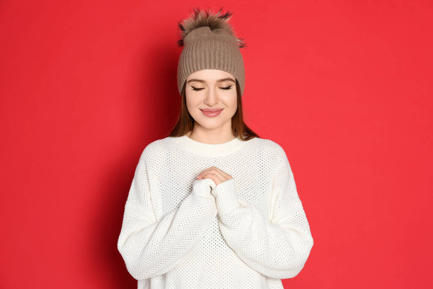 Young woman wearing warm sweater and hat on red background. Winter season - Foto, immagini