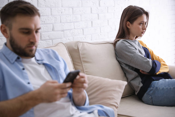 Young man preferring smartphone over his girlfriend at home. Relationship problems - Foto, Imagem