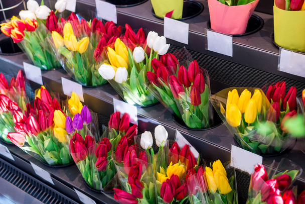 close-up van vele roze, rode, gele tulpenboeketten in een bloemenwinkel, bloemenmarkt of winkel. Groothandel en detailhandel. Moederdag en vrouwendag - Foto, afbeelding