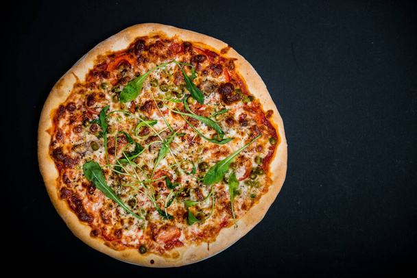 Итальянская пицца с зеленью на черном столе с копировальным местом
 - Фото, изображение