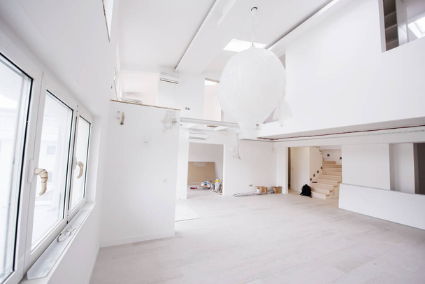 Interior of empty stylish modern open space two level apartment with white walls and large round chandelier in the middle ready to move in - Fotó, kép