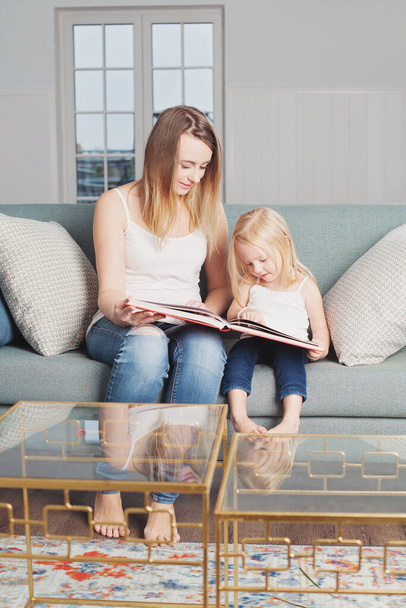 Mutter und kleine Tochter lesen zu Hause ein Buch - Foto, Bild