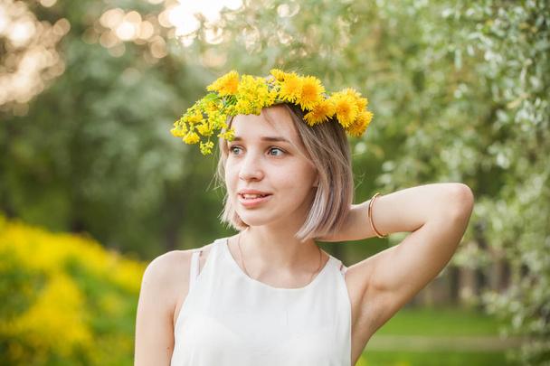 Outdoors portrait of attractive young woman in dandelions flowers wreath - Photo, Image