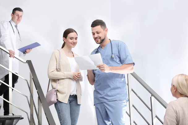 Doctor and patient discussing diagnosis on stairs in hospital - Photo, image
