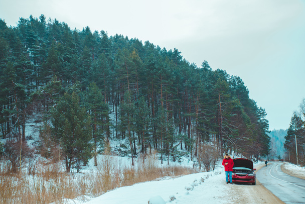 uomo in piedi vicino rotto auto a bordo strada nevicato tempo invernale. copia spazio - Foto, immagini