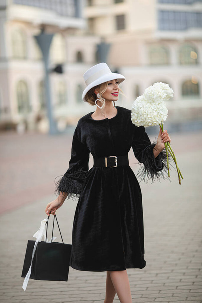 Heureuse femme élégante avec des fleurs posant à l'extérieur
 - Photo, image