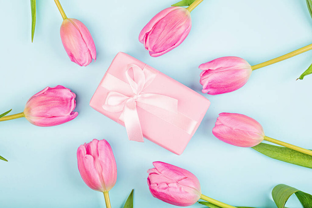 View from above tulips and gift box with copy space on blue. Background for womens day, 8 March Valentines day, 14 february. Flat lay style, top view, mock up, template, overhead. Greeting card - 写真・画像