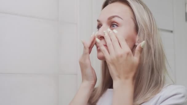 CLose up of Elegant young woman looking at mirror and touching her face in bathroom - Filmagem, Vídeo