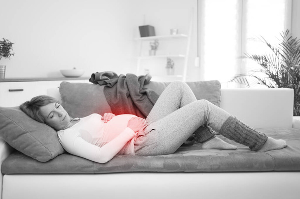 Беременная уставшая измученная женщина с проблемами желудка дома на диване, болеющая
. - Фото, изображение