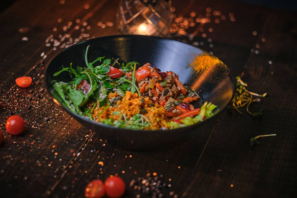 Cuenco vegetariano saludable de plov servido en una mesa de madera decorada con especias en una luz suave oscura de un restaurante
 - Foto, imagen