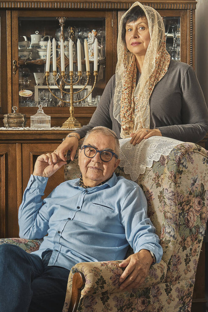 Єврейська старша пара постає на кріслі в традиційному будинку.  - Фото, зображення