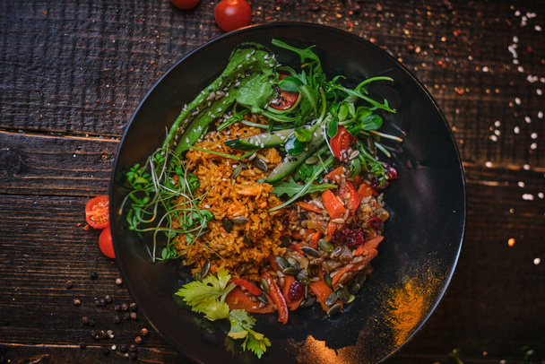 Cuenco vegetariano nutritivo de plov servido en una mesa de madera decorada con especias en una luz suave oscura de un restaurante
 - Foto, imagen