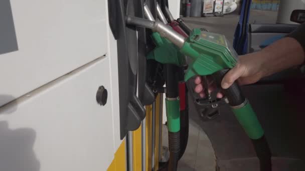 Männliche Hand hält eine Benzindüse in einer Tankstelle. Zeitlupe - Filmmaterial, Video