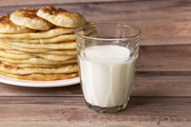 Sağlıklı köy yemekleri. Kahvaltıda süt, bir bardak ve sıcak kek. Buğday, mısır unu kekleri. Ağaç sırtı - Fotoğraf, Görsel
