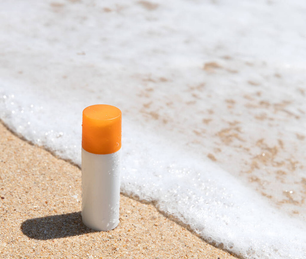 Bottle of sunscreen lotion on the sandy beach by the sea. Health skin care sun protection concept. Cosmetics with natural ingredients. - Photo, Image