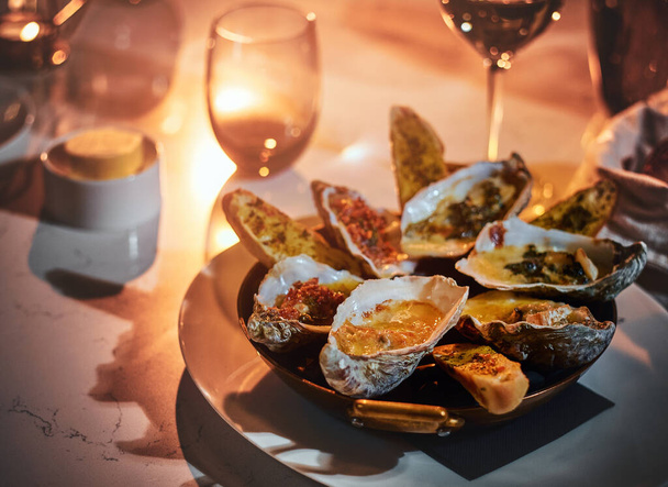 Cozinha alta jantar tigela de ostras e pão loafs com molho servido em uma mesa ao lado de vela, e um copo de vinho, em um restaurante
 - Foto, Imagem