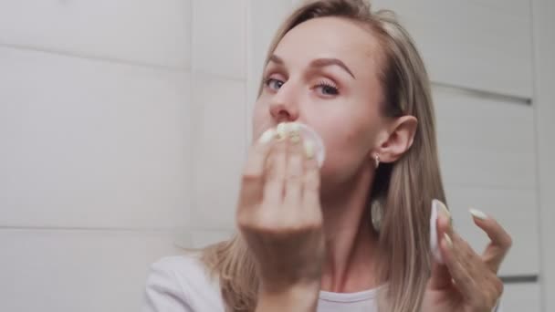 Woman applying lotion and looking at the camera - Кадри, відео