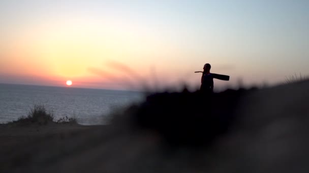 Silhouette de jeune homme chantant en plein air jouant de la guitare acoustique au coucher du soleil
 - Séquence, vidéo