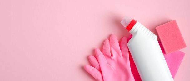 ピンクの背景に掃除用品。清掃サービスとハウスキーピングのコンセプト。トップビュースプレーボトル、スポンジ、ゴム手袋、洗浄洗剤. - 写真・画像