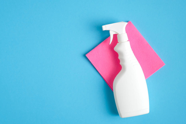Blank cleaning spray bottle and pink rag on blue background. Flat lay, top view. House cleaning service and housekeeping concept. - Fotoğraf, Görsel