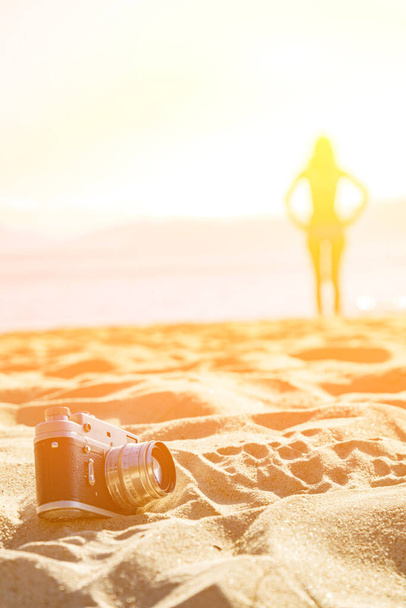 Retro-Analogkamera am Strand mit Frauensilhouette im Hintergrund. - Foto, Bild