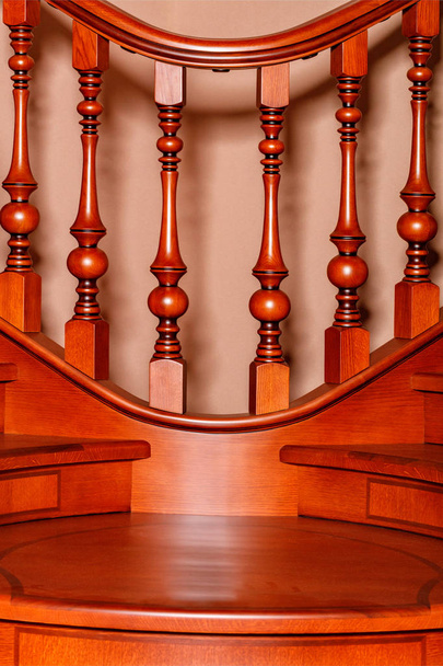 Θραύσμα όμορφο από μια ξύλινη σκάλα με σχήμα σκαλιστά balusters και κάγκελα και φιμέ μαόνι. - Φωτογραφία, εικόνα