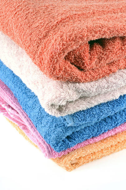 Serviettes de bain de différentes couleurs pliées et empilées gros plan sur fond blanc
 - Photo, image