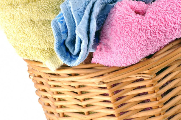 Ręczniki w różnych kolorach w wiklinowym koszu z bliska na białym tle  - Zdjęcie, obraz