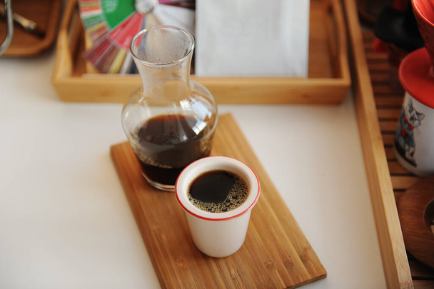 Black filter coffee is served in glass decanter with cup on wooden tray. Manual brewing still life. Third wave specialty aesthetics - Photo, Image