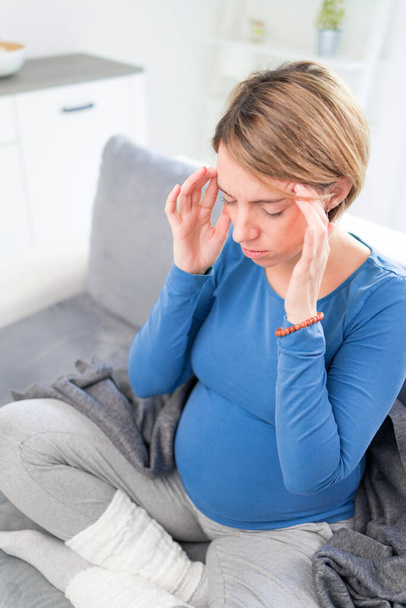 Donna stanca incinta esausta con problemi di stomaco e testa a casa su un divano, essendo malata
. - Foto, immagini