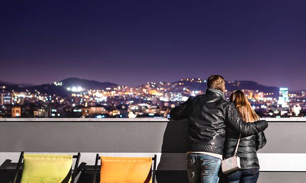Das urbane Paar betrachtet die Stadt vom Dach aus. Freund hält Arm um seine Freundin. Romantischer Abend für Date. Vertrauen und Romantik. Glückliche Liebende in Barcelona. Kopierraum am Himmel. - Foto, Bild