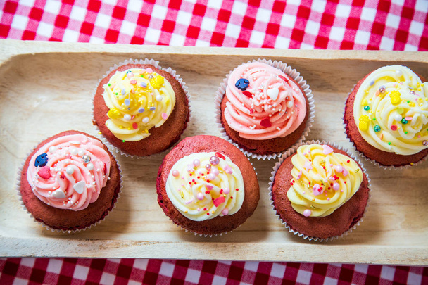 Red velvet cup cakes with white and rose topping from a fresh butter cream. Together with small colourful sprinkles like an anchor or also pineapple. Each from a different focus.  - Photo, Image