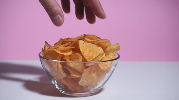 hand man neem aardappel chip close-up. op een roze achtergrond - Video