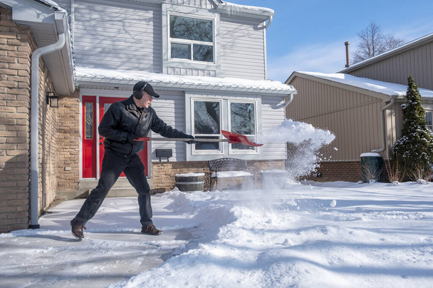 Ember eltávolítása hó egy piros lapáttal a ház előtt - Fotó, kép