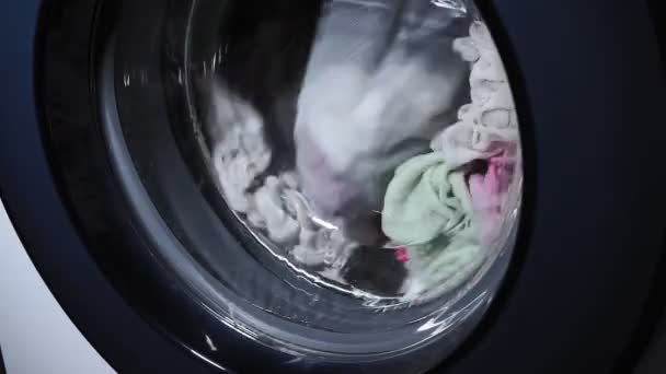 Mosógép színes ruhákkal dolgozik. Közelkép, Ipari mosoda. - Felvétel, videó