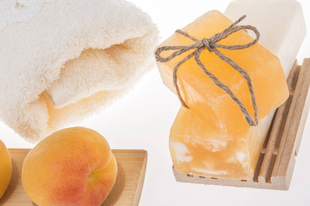 Stapel natürlicher Seifenstäbe, Aprikosenfrüchte und Handtuch auf weiß - Foto, Bild