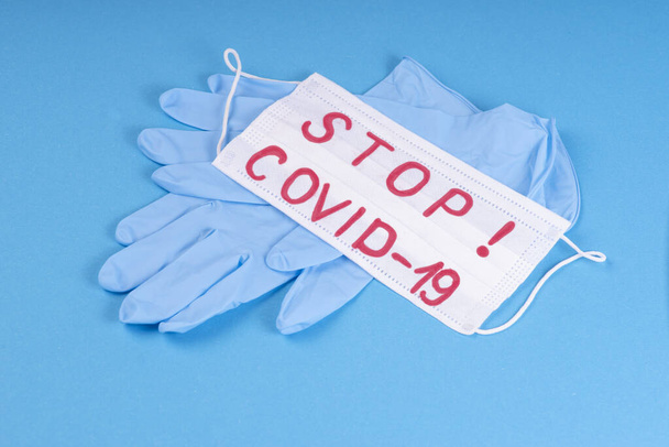 Blue medical gloves on a blue background with a white medical mask with a respirator.Respirator mask a mandatory personal protective equipment.Covid-19,coronovirus - Photo, Image