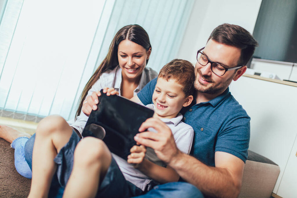 Familia feliz disfrutando juntos en casa, usando tableta y pasando un buen rato juntos
. - Foto, Imagen