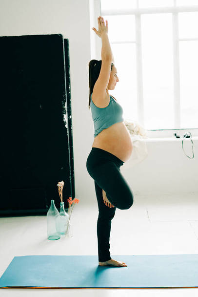 young pregnant girl in sportswear doing yoga, doing asana - 写真・画像