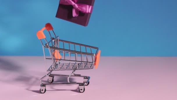 gifts in a shopping cart on a blue pink background. Abstract design element, annual sale, shopping season concept. - Footage, Video