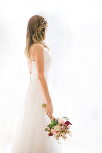 Come in front of the white background. She has a bridal flower in her hand. - Фото, изображение