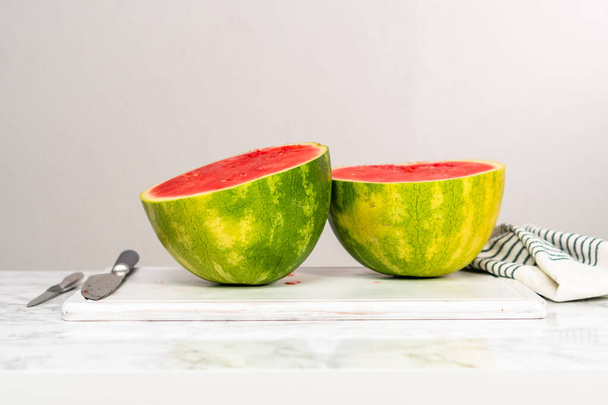 Slicing red seedless watermelon on a white cutting board. - Photo, Image