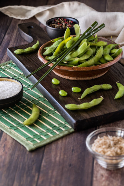 Close up of a rustic bowl filled with fresh organic edamame beans in their pods. - 写真・画像