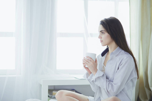 Mulher sentada na cama lendo um livro e tomando café da manhã - Foto, Imagem