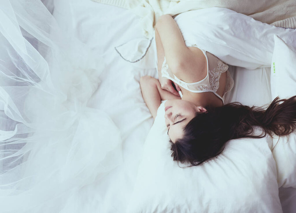 Pretty woman lying down on her bed at home - Фото, зображення